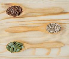 Dry flax,  sesame and pumpkin seeds in wooden spoon photo