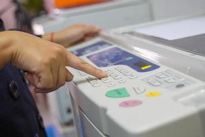 office worker Pressing a number button on the copier to specify the number of documents to be copied. soft and selective focus. photo