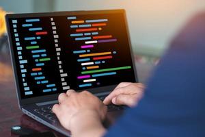 A man is typing on the laptop with virtual code graphic on screen photo