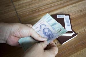 woman hand hold for counting vietnam dong banknote  with passport book on  wood table photo