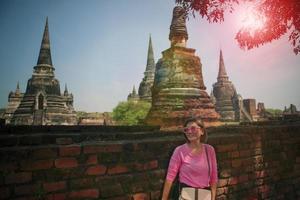 beautiful woman standing against old brick wall with asian temple background photo