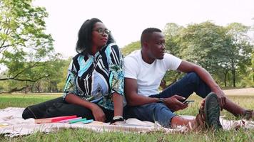 content charmant Jeune africain américain couple pique-nique dans le parc et parlant dans de bonne heure tomber