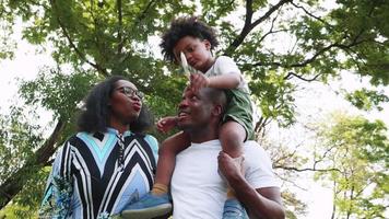 feliz africano americano família, filho estava feliz em Papai ombro dentro parque video