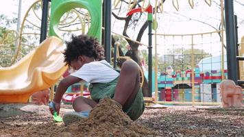 Afrikaanse Amerikaans kind hebben pret spelen met zand in speelplaats