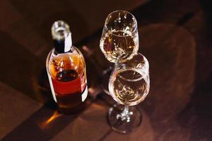 Rose wine bottle with glasses on wooden table at dinner time. photo