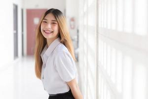 retrato de linda tailandés estudiante en Universidad estudiante uniforme. joven asiático hermosa niña en pie sonriente con confianza a universidad. foto