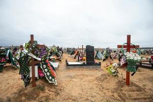 Grave crosses with wreaths in the cemetery on the sand photo