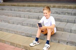 The boy sits on the steps and takes a selfie photo