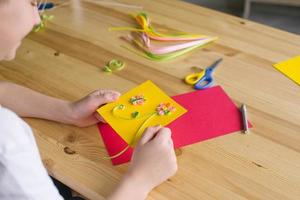 The child is holding a postcard for mom, made by his own hands quilling photo