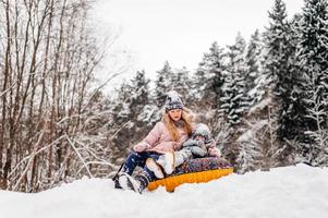 Boys and a girl are sitting in a tubing in the snow photo