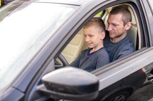 Dad shows his little son how to drive a car photo