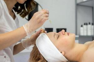 Cosmetologist drips serum on the girl's face photo