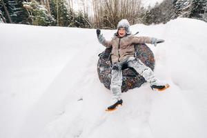 un chico es sentado en un tubería en el nieve y montando abajo un diapositiva foto