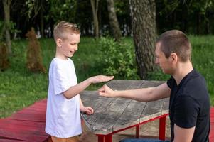 A cute boy is playing a game with his dad. shows signs with his hands photo