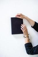 Women's hands are lying on a black book photo