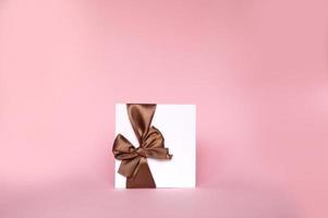 A gift envelope with a bow, with an empty copy space on a pink background. Flat stands photo