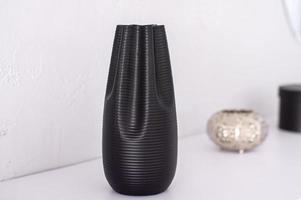 A black empty vase with stripes is on the shelf photo