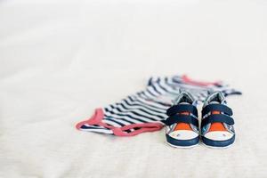 Children's blue sneakers in women's hands on the background of blankets and children's clothes photo