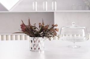 Grey glass vase and decorative floral elements on a white table photo