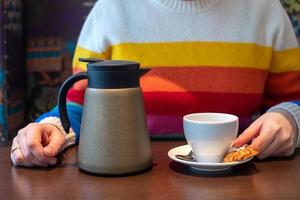 hembra manos verter verde té desde un tetera dentro un blanco taza foto