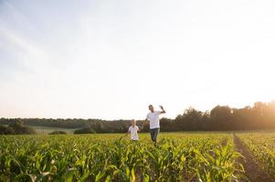 Cute boy in a cornfield with dad launching a plane photo