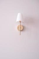 A lamp with golden elements hangs on the pink wall photo