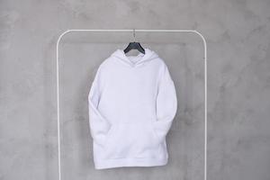 A set of mockups of a white hoodie with a hood and a pocket hanging on a hanger photo