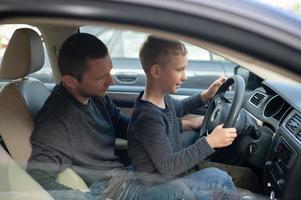 Dad shows his little son how to drive a car photo