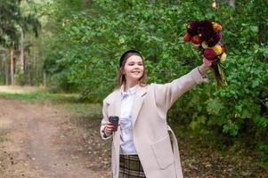 un linda niña Bebiendo café elevado su mano con flores arriba foto