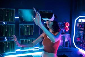 un joven asiático mujer utilizando virtual realidad , vr caja a jugar en línea juego o reloj película foto