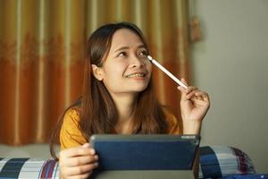 Asian woman happy after watching profit from computer on the bed working from home photo