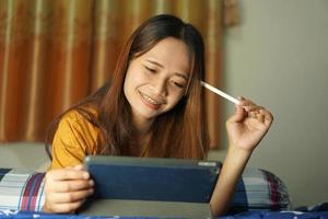 Asian woman happy after watching profit from computer on the bed working from home photo