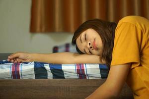 asiático mujer dormido en el cama debido a difícil trabajo foto