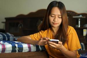 happy asian woman Looking at the phone, knowing that profits are higher, work from home. photo