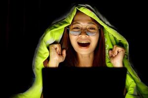 Asian woman wearing glasses To view the computer in low light watch movies online photo