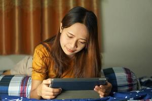 Asian woman happy after watching profit from computer on the bed working from home photo