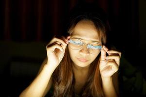 Asian woman wearing glasses To view the computer in low light watch movies online photo