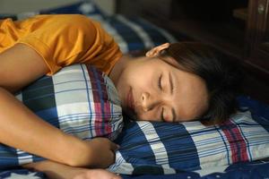 asiático mujer dormido abrazando un almohada en el cama foto
