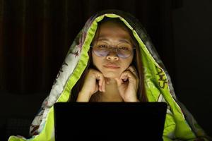Asian woman wearing glasses To view the computer in low light watch movies online photo