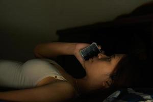 Asian woman using phone on bed photo