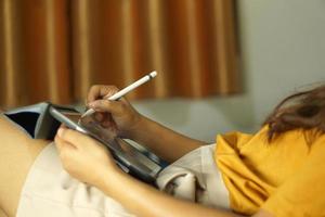 Asian woman working on a computer on the bed working from home photo