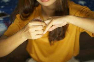 asiático mujer quitando Boda anillo desde mano foto