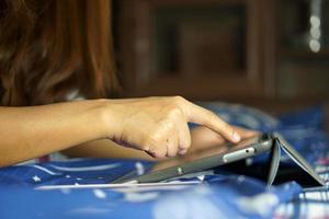 asiático mujer trabajando en un computadora en el cama trabajando desde hogar foto