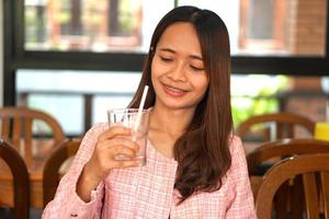 Asian woman drinking water in glass photo