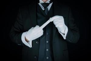 retrato de mayordomo en oscuro traje y blanco guantes haciendo grosero gesto. concepto de rebelión foto