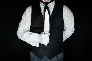 Portrait of Butler in Black Vest and White Gloves Holding a Sharp Knife. Concept of Butler Did It. photo