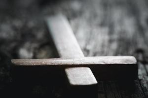 A wooden Christian cross crucifix on a grunge board background. Wooden Christian cross on grey table against blurred lights, space for text. photo