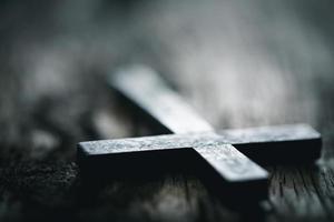 A wooden Christian cross crucifix on a grunge board background. Wooden Christian cross on grey table against blurred lights, space for text. photo