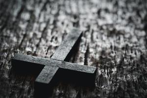 A wooden Christian cross crucifix on a grunge board background. Wooden Christian cross on grey table against blurred lights, space for text. photo