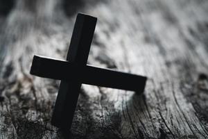 A wooden Christian cross crucifix on a grunge board background. Wooden Christian cross on grey table against blurred lights, space for text. photo